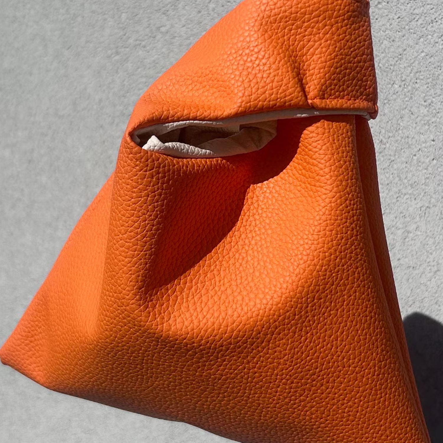 Vibrant Tangerine Orange Pebbled Grain Knotted Wrist Pouch With Contrast Pale Beige Inner Lining And Japanese Wrap Handle Silhouette