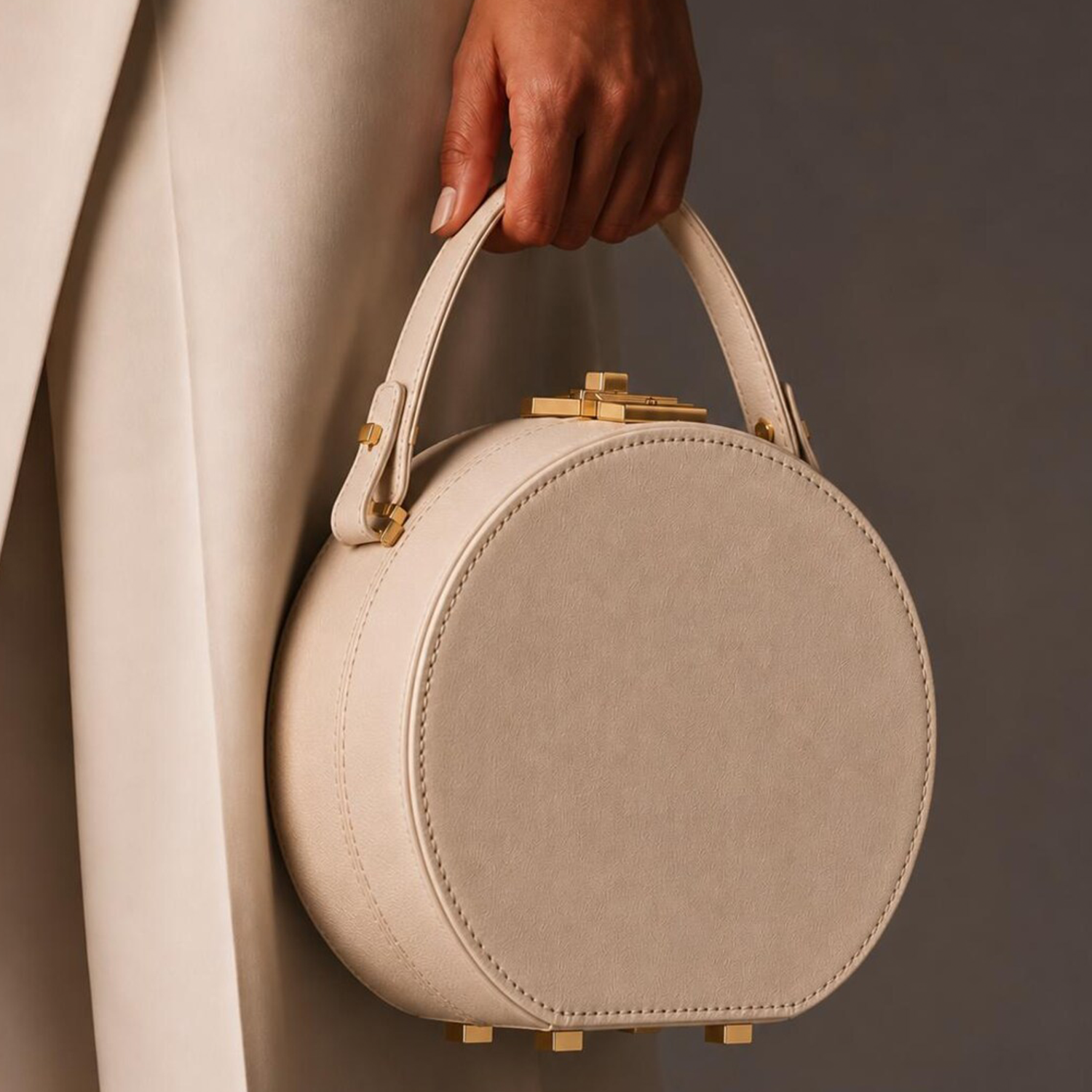 Soft Cream Beige Pebbled Grain Rigid Circular Hatbox Handbag With Curved Fixed Top Handle, Rectangular Gold Twist-Lock Clasp And Protective Base Foot Stud Hardware