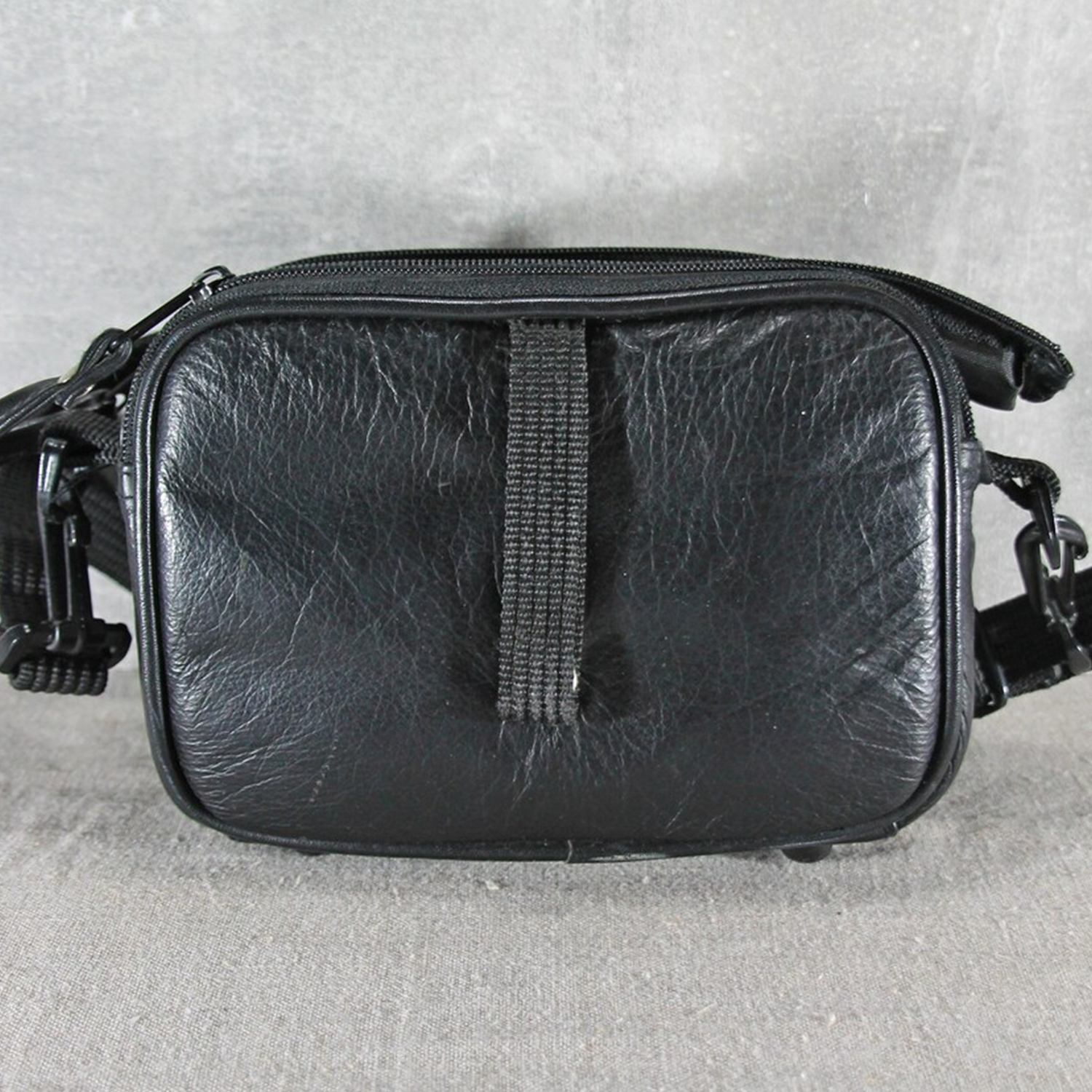 Matte Jet Black Naturally Wrinkled Grain Compact Rectangular Gear Pouch With Dual Stacked Front Zip Compartments And Woven Fabric Clasp Mount Strap Hardware Camera Bag